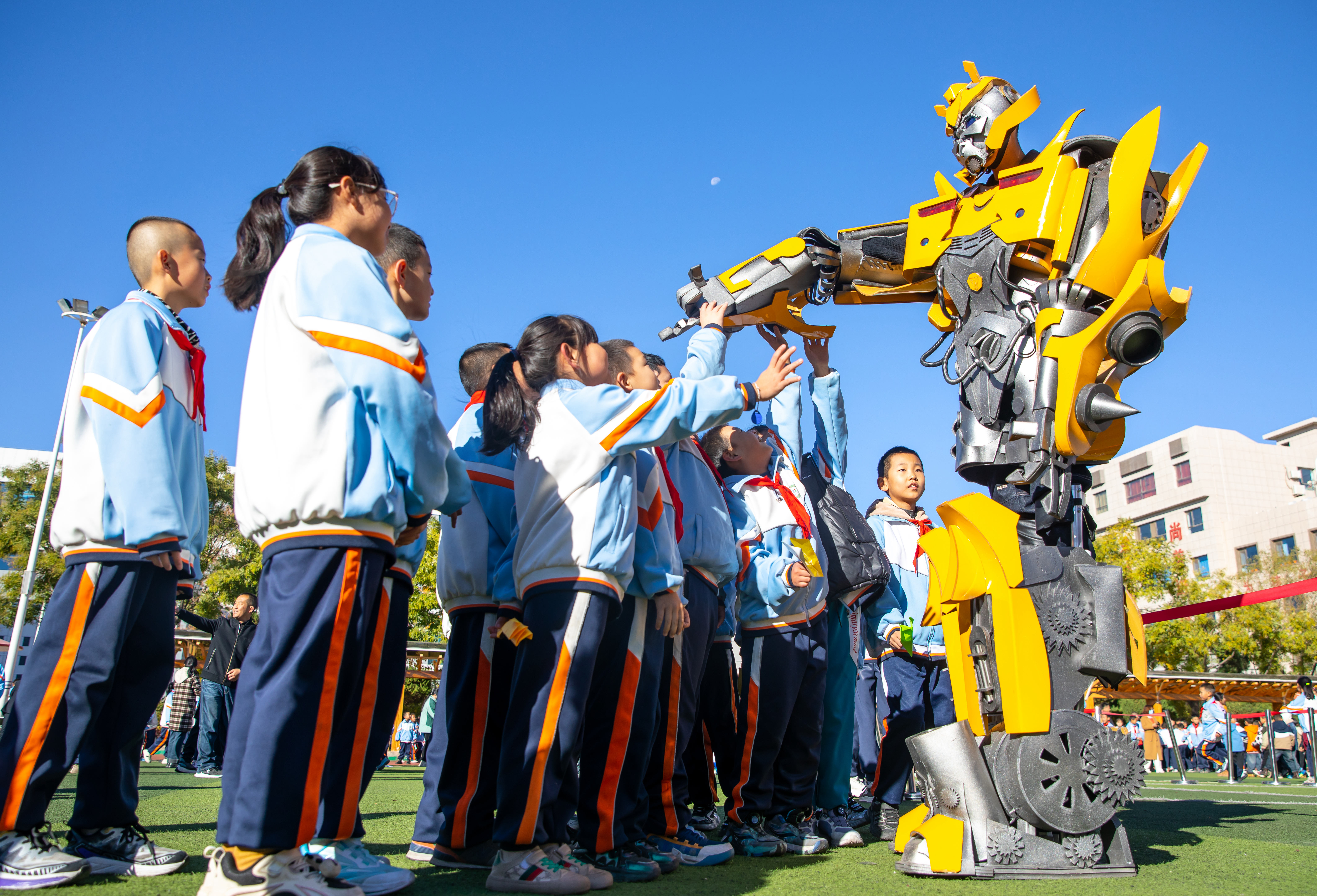 2024年10月22日，在甘肅省張掖市甘州區(qū)北街街小學(xué)科技大篷車嘉年華活動(dòng)上，學(xué)生與“大黃蜂”機(jī)器人互動(dòng)。楊瀟 攝.jpg