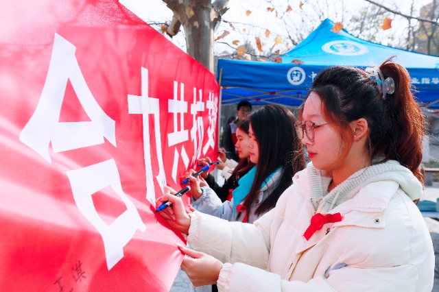 20231127中國石油大學(xué)（華東）青年學(xué)子在合力共抗艾滋的條幅上簽字，表達(dá)抗擊艾滋病的決心和信心  .jpg