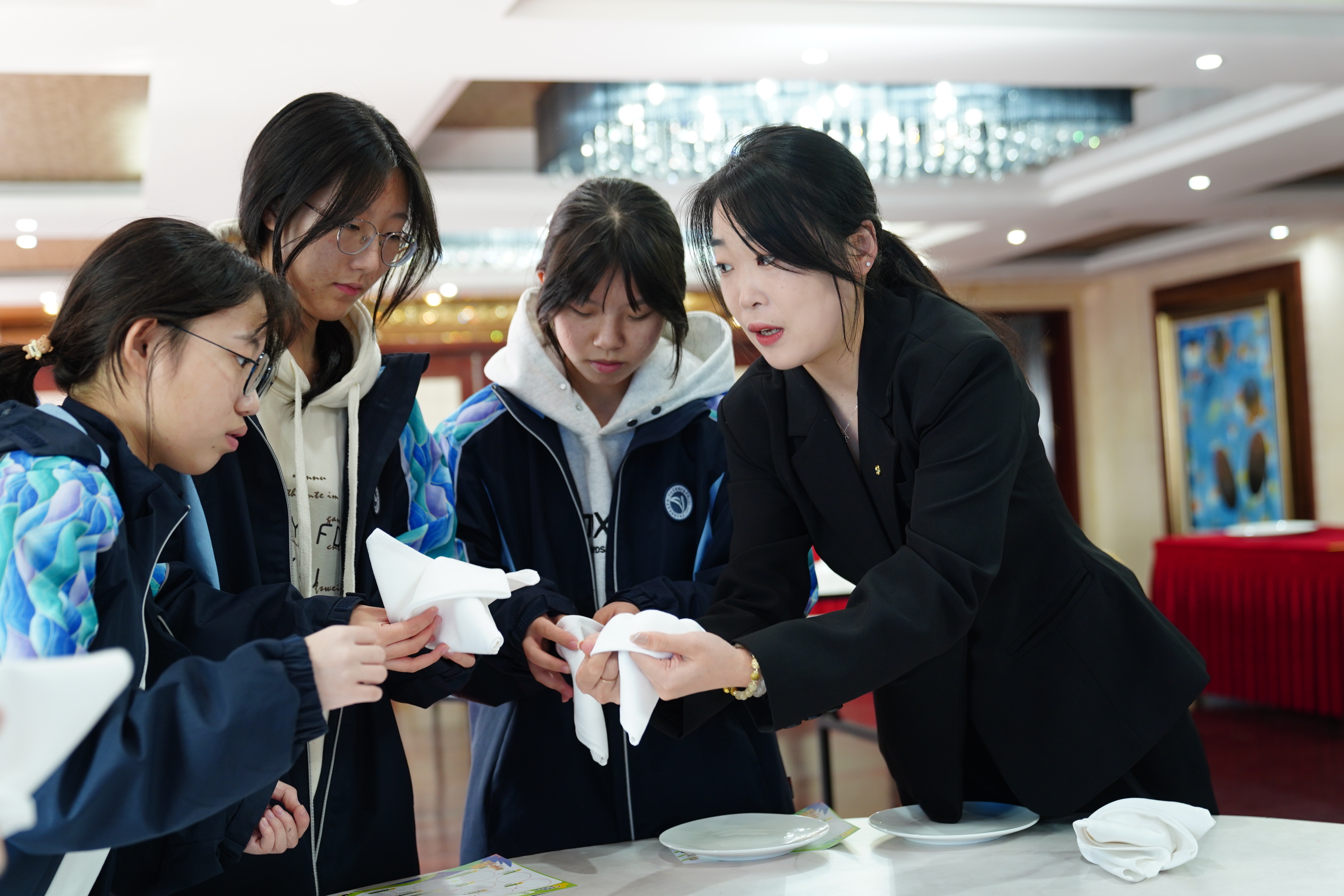 寧波東錢湖旅游學校學生在企業(yè)導師（右一）的指導下體驗指尖藝術(shù)(中餐擺臺)項目 胡佳 攝.jpg